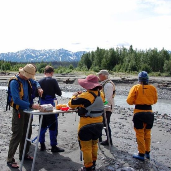 Raft guides and guests eating lunch on the river - Explore McCarthy