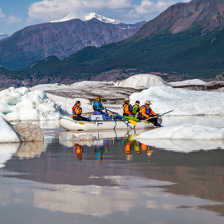 Explore McCarthy - Whitewater rafters on the Nizina River with large glaciers